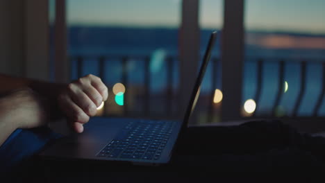 young man using laptop lying in bed browsing online finished working late at night looking at watch