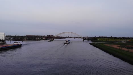 barcaza industrial navegando por el río noord con puente de arco en la distancia