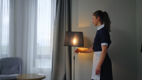 maid turning on a lamp in a hotel room