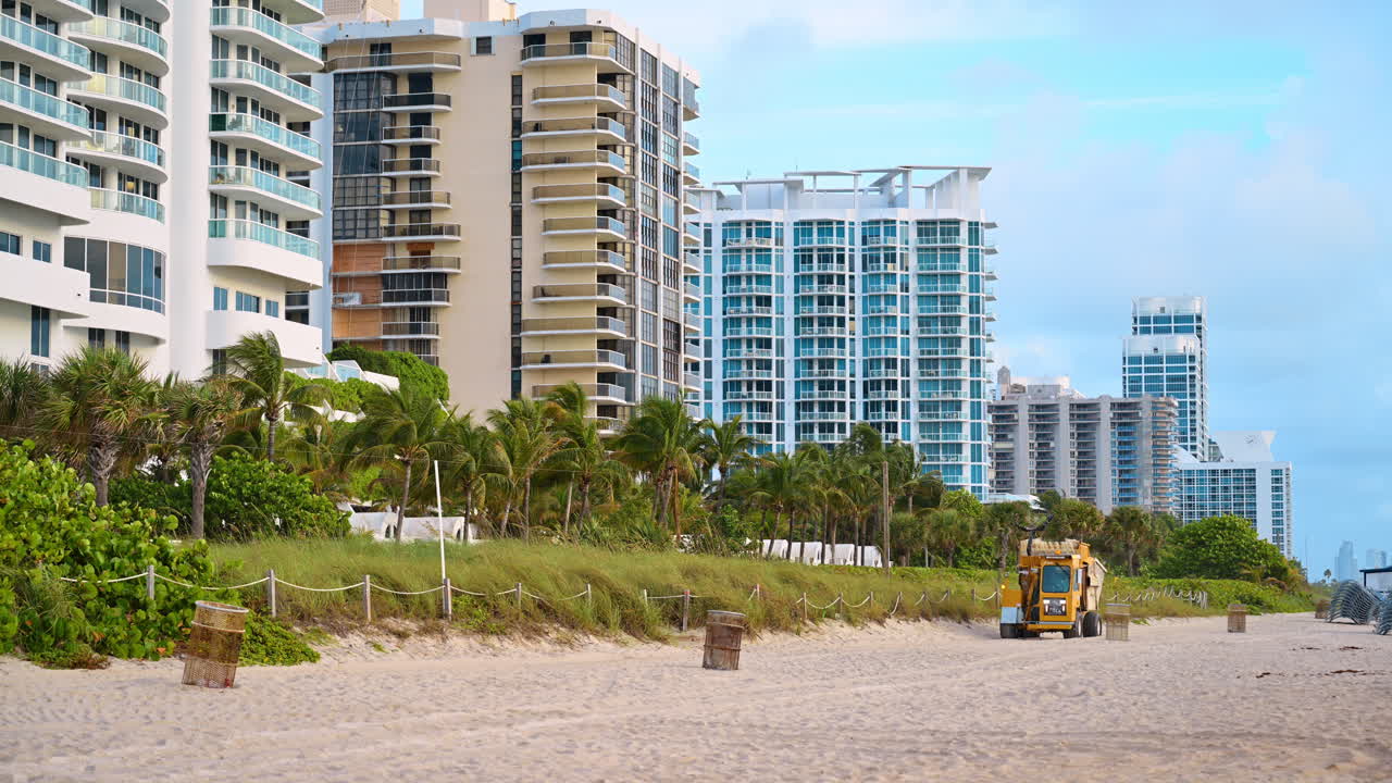 Condominios de lujo frente a la playa y palmeras en Miami Beach. Modernos edificios de apartamentos de gran altura con vistas a la playa de arena, palmeras y un vehículo utilitario.