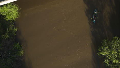 two people kayaking on the muddy waters of wolf river, collierville, tennessee, surrounded by trees, aerial view