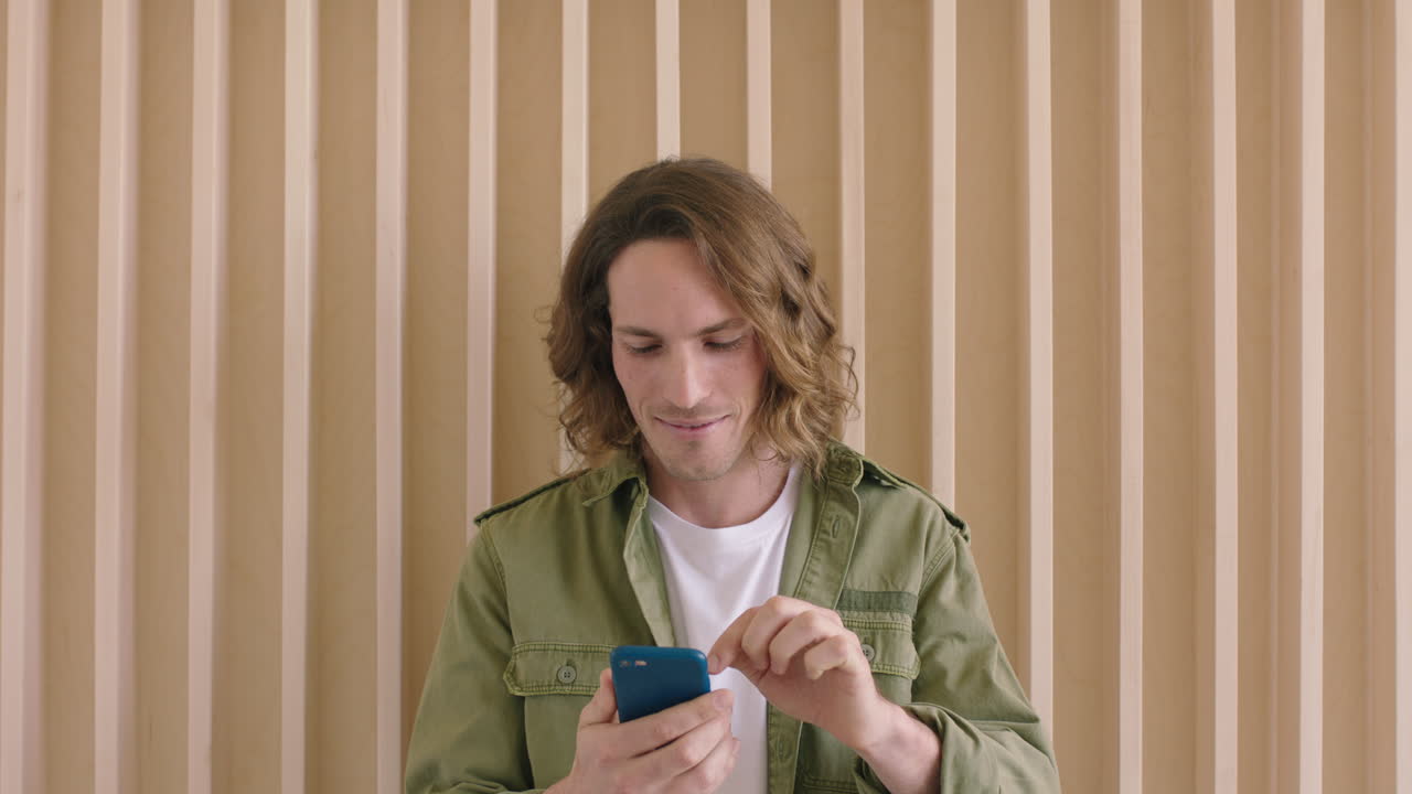 ritratto di un bel giovane uomo caucasico che invia messaggi di testo, naviga online utilizzando lo smartphone, utilizza la tecnologia mobile e gode della comunicazione digitale