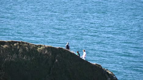 people-stand-on-a-grassy-cliff-in-the-south-of-England,-seaside-landscape