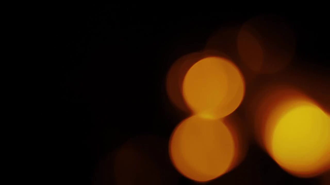 Abstrakte glødende bokeh-lyscirkler i bevægelse på mørk baggrund