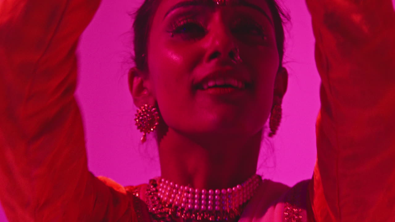 up cerca en la cara de la bailarina de kathak femenina realizando el baile con el vestido tradicional indio contra un fondo púrpura