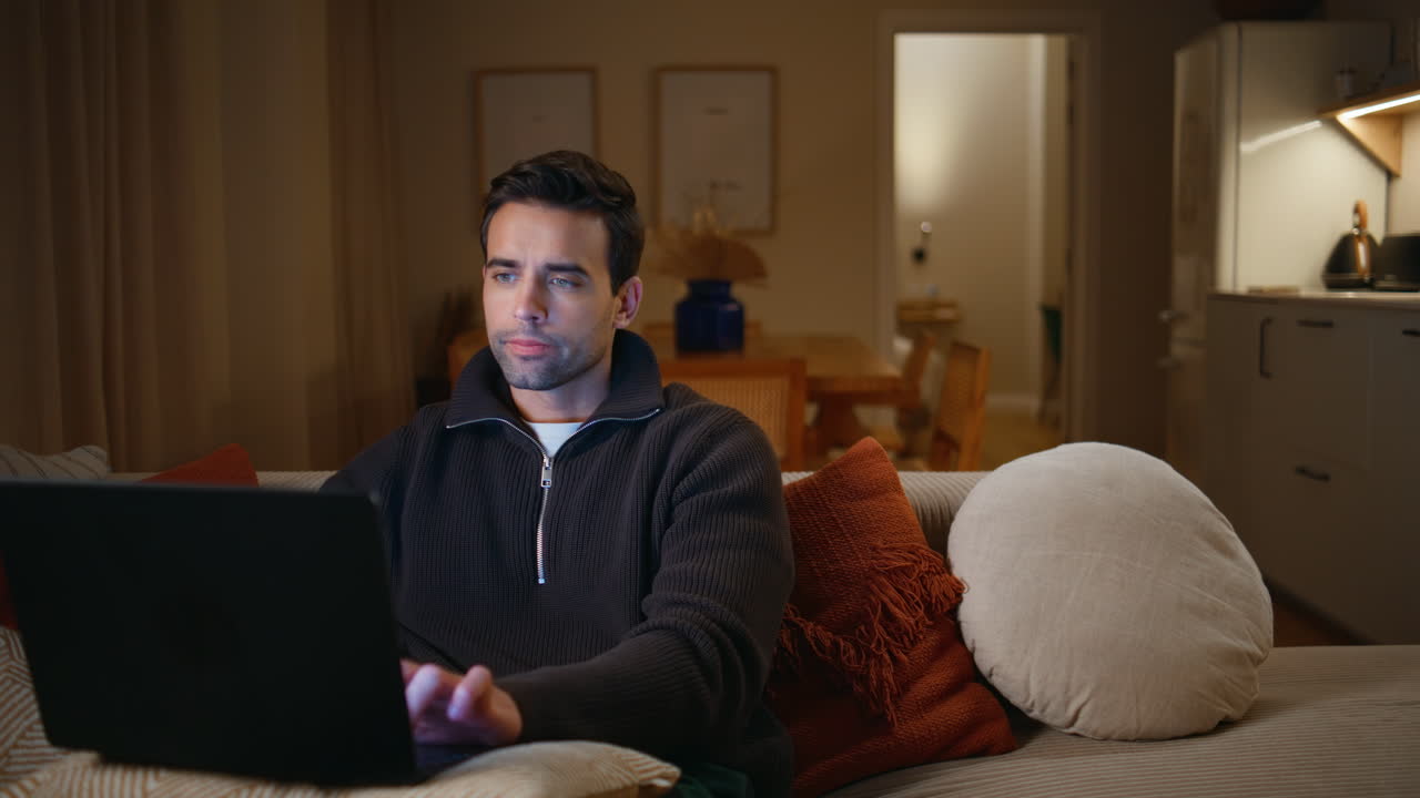Man developer working computer sitting cozy couch living room. Man typing laptop