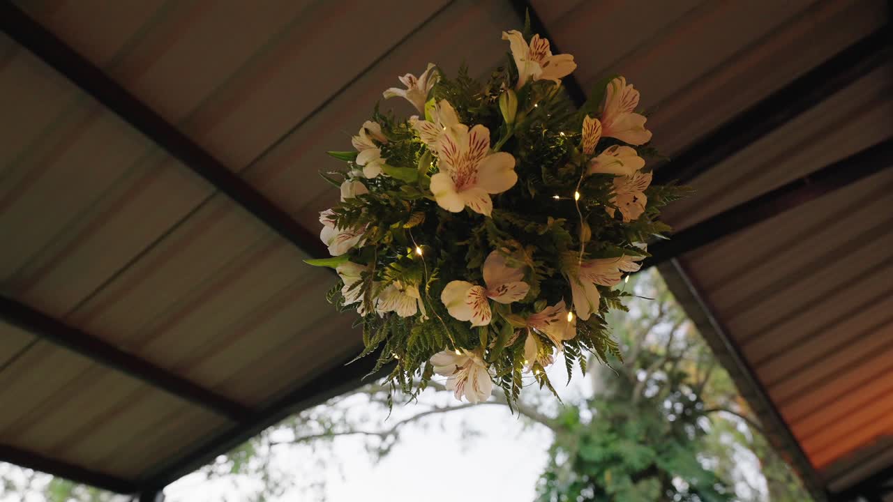 Hanging floral arrangement with white flowers greenery and warm decorative lights for wedding decor