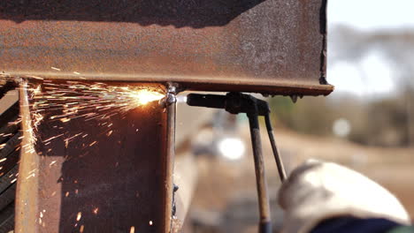 slow-motion of blowtorch cutting through rustic metal