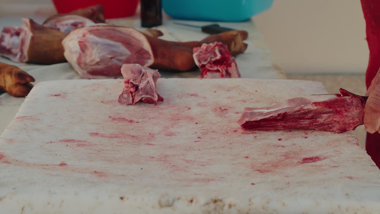 cleaver chops bloody pork bone on stained white cutting surface