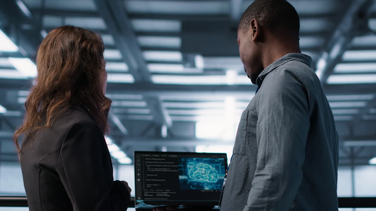 Software developers in data center using laptop, employing AI machine learning