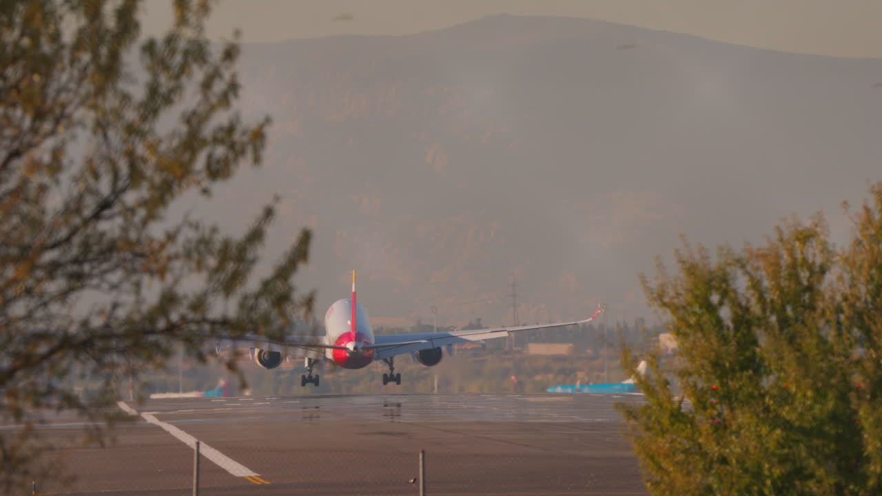 Stort passagerarflygplan som landar på flygplatsens landningsbana i solnedgången