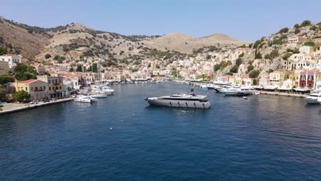 large luxurious super yacht in the port of symi in greece, aerial backward