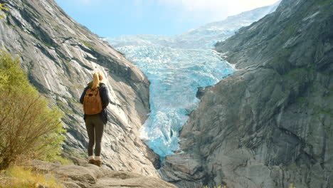 mujer en noruega, caminando con los brazos abiertos, por un glaciar