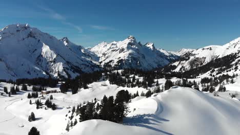 captivating panoramic drone view of snow-covered mountain ranges in warth, a small municipality in vorarlberg, austria on a sunny day with clear blue skies in 4k