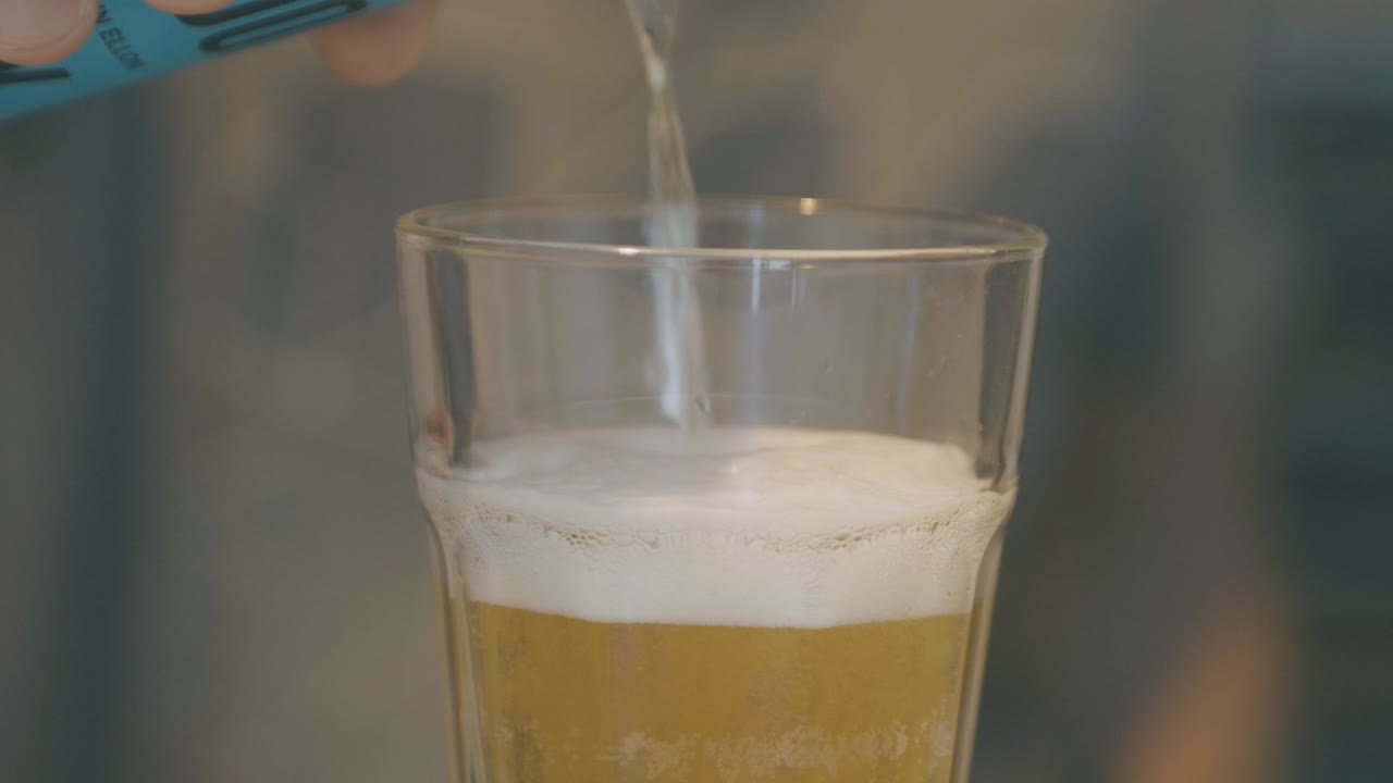 un tipo vierte cerveza en un vaso a cámara lenta, detalles de la espuma ascendente