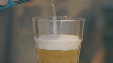 a guy pours beer into a glass in slow motion, details of the rising foam