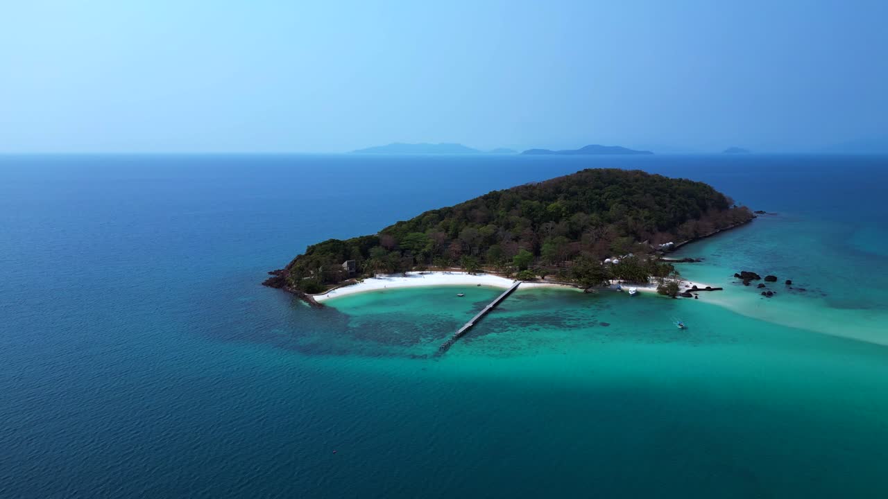Koh Kham Island with its green tropical vegetation surrounded by crystal clear turquoise waters, Thailand. Unique aerial view flight wide orbit overview drone