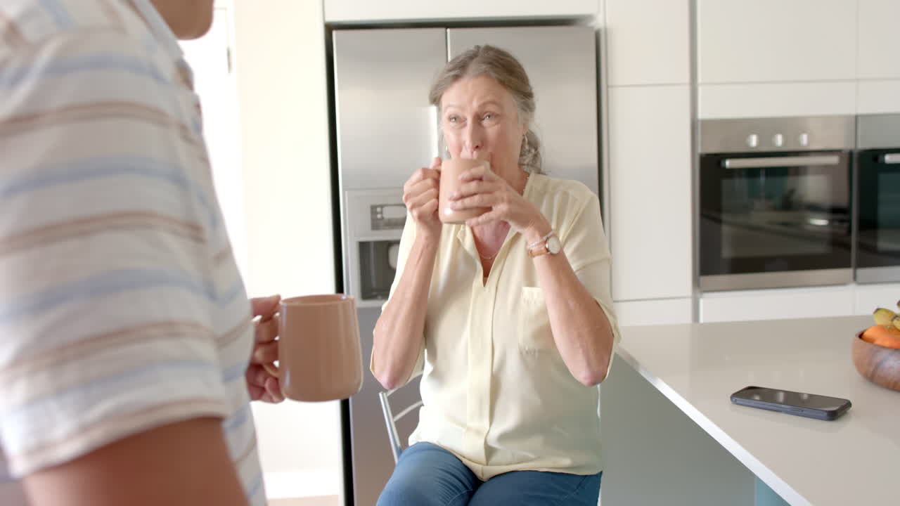 Drinking coffee, senior woman smiling and talking with partner in kitchen