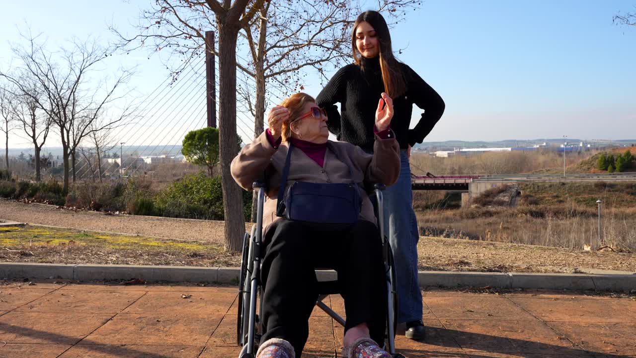 Elderly woman receiving hug and kiss from her granddaughter in park
