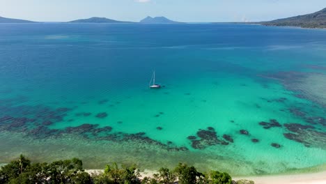 aerial drone shot of holiday destination with sail boat yacht in rocky sand bay with tropical island travel tourism beach efate siviri port vila vanuatu 4k