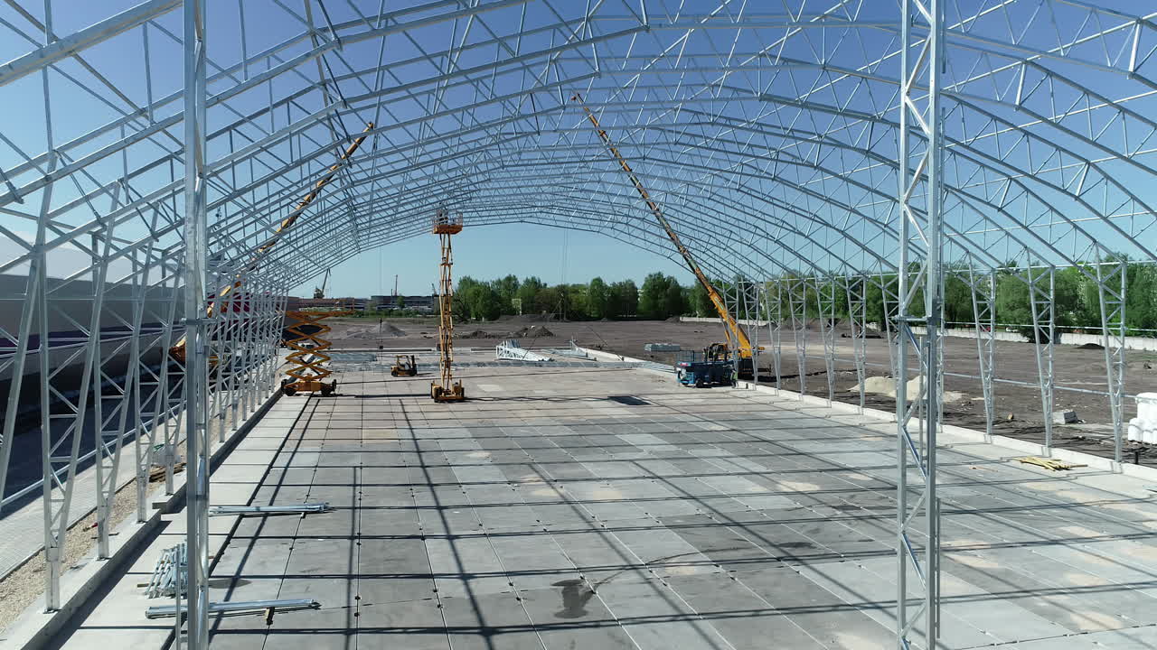 노란색 크레인 에 의해 건설 되고 있는 대형 산업 건물 의 골격