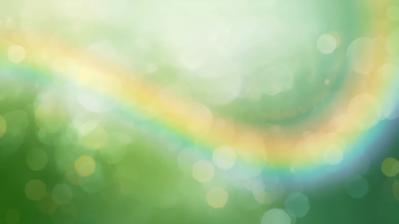 左から現れ、緑の背景を滑るように横切る虹色のリボン、脈動するボケが太陽の光を思わせる。