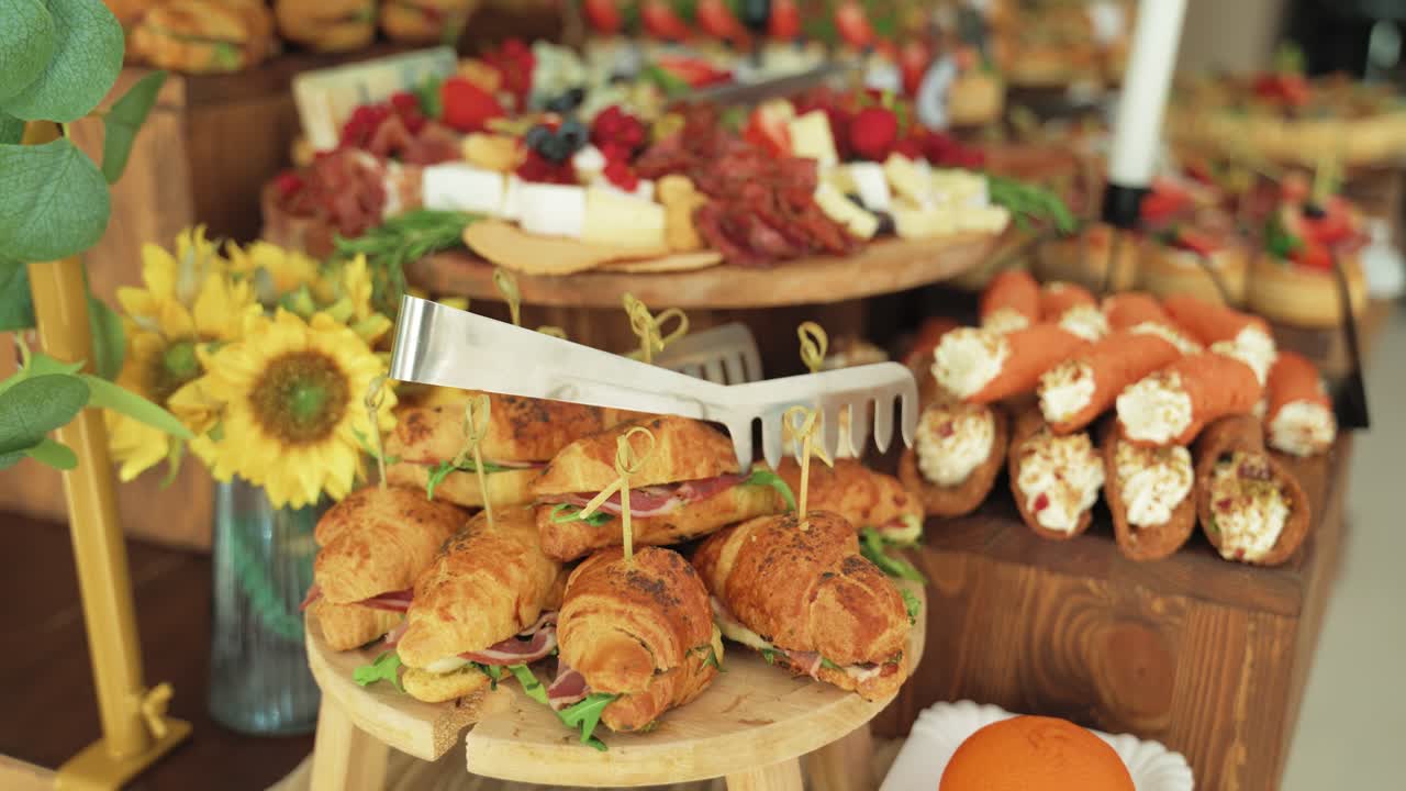 Croissants cut in half, filled with savory meat and fresh salad, alongside cheese rolls, close up shot of a snack bar
