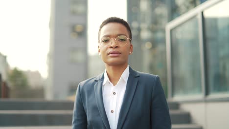 portrait confident serious african american business woman standing on urban office center looking at camera. outdoor.