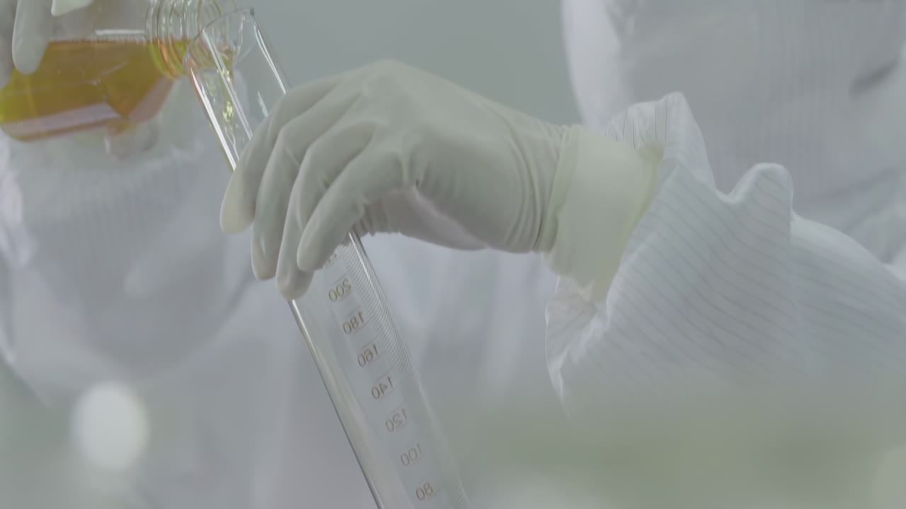Professional doctor, chemist or scientist equipped with protective suits, face masks, safety goggles, loads liquid sample into flask for biochemical testing laboratories, innovation in medicine