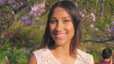 portrait of a young woman smiling in front of cherry blossoms