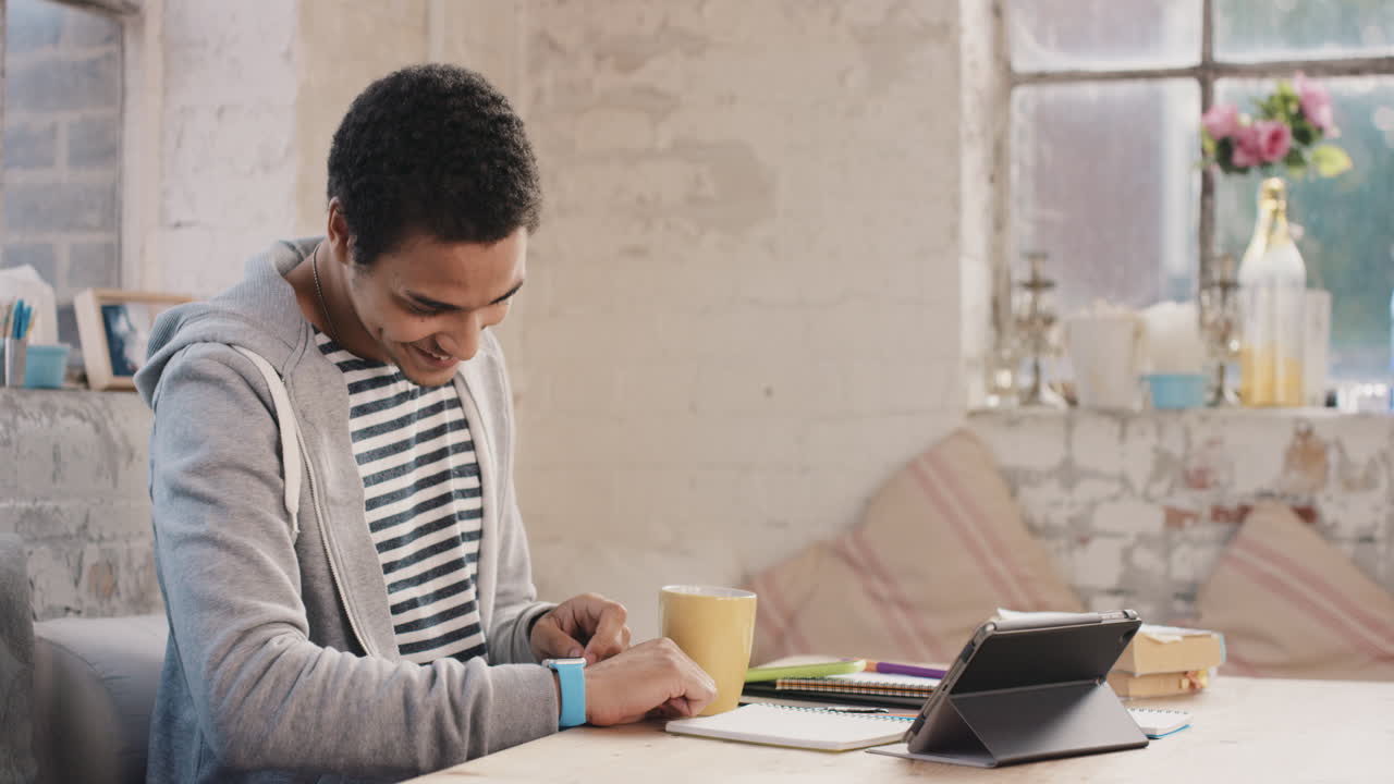 Young student using smart watch at home in  morning drinking coffee