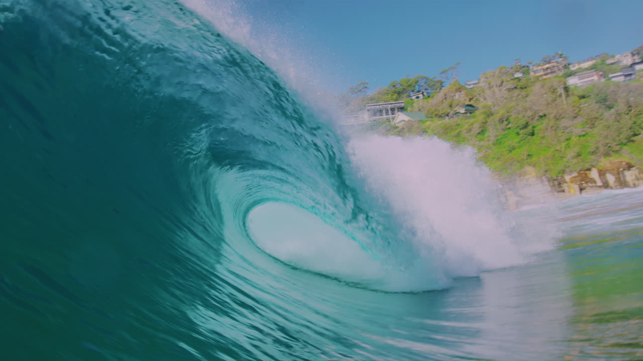 Slow-motion ocean wave crashing near the shore, shot from the water at early morning, capturing the power and spray of the wave