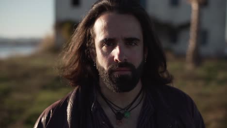 man with long hair in front of an abandoned building