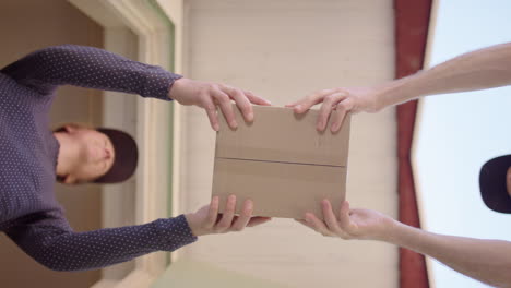 home owner at door takes delivery of small carton box, low upward view