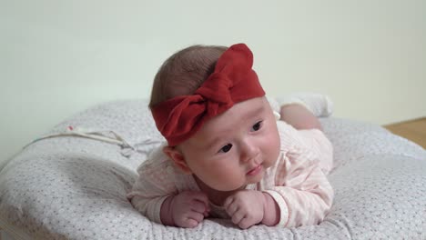 newborn infant baby girl struggling to lie on belly trying to keep head up