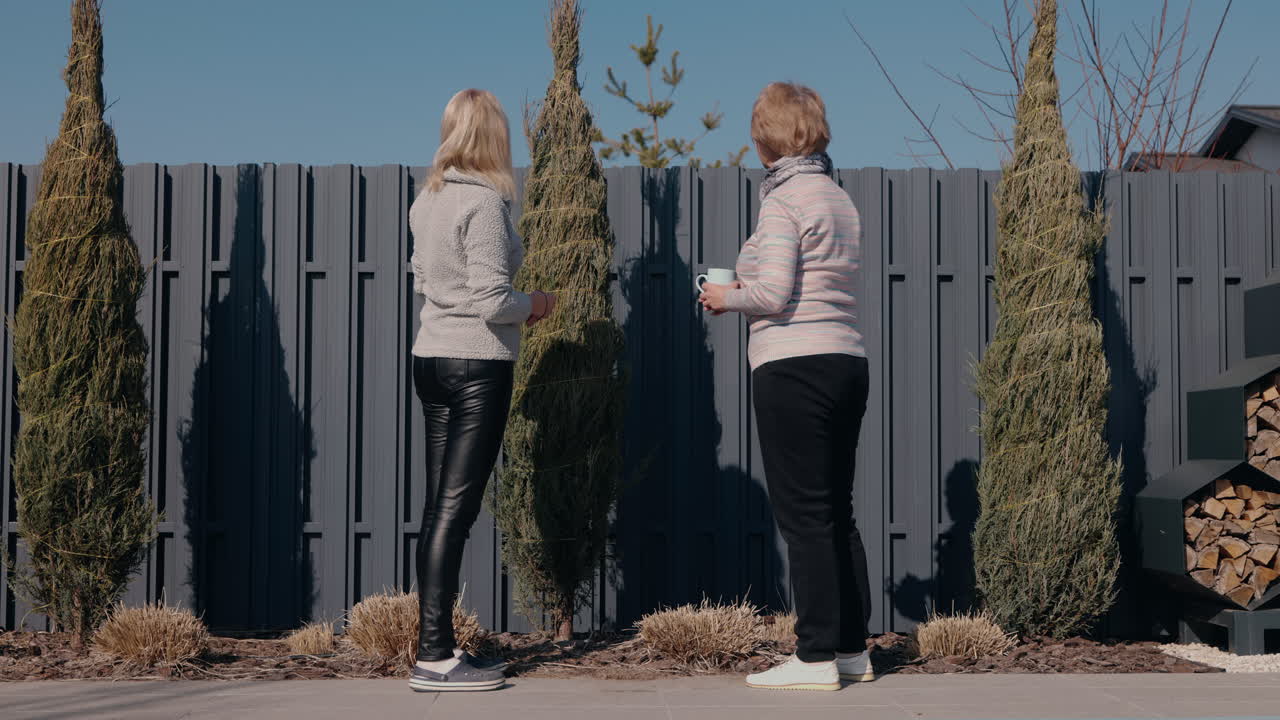 두 여인이 울타리 에서 정원 가꾸고 있다