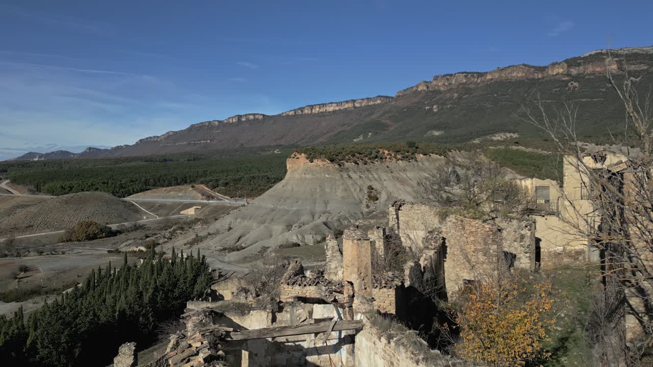 Betagende panoramaudsigt over ruinerne af den forladte middelalderlandsby Esco i Aragon, Spanien, med Pyrenæerne i baggrunden på en solrig efterårsdag