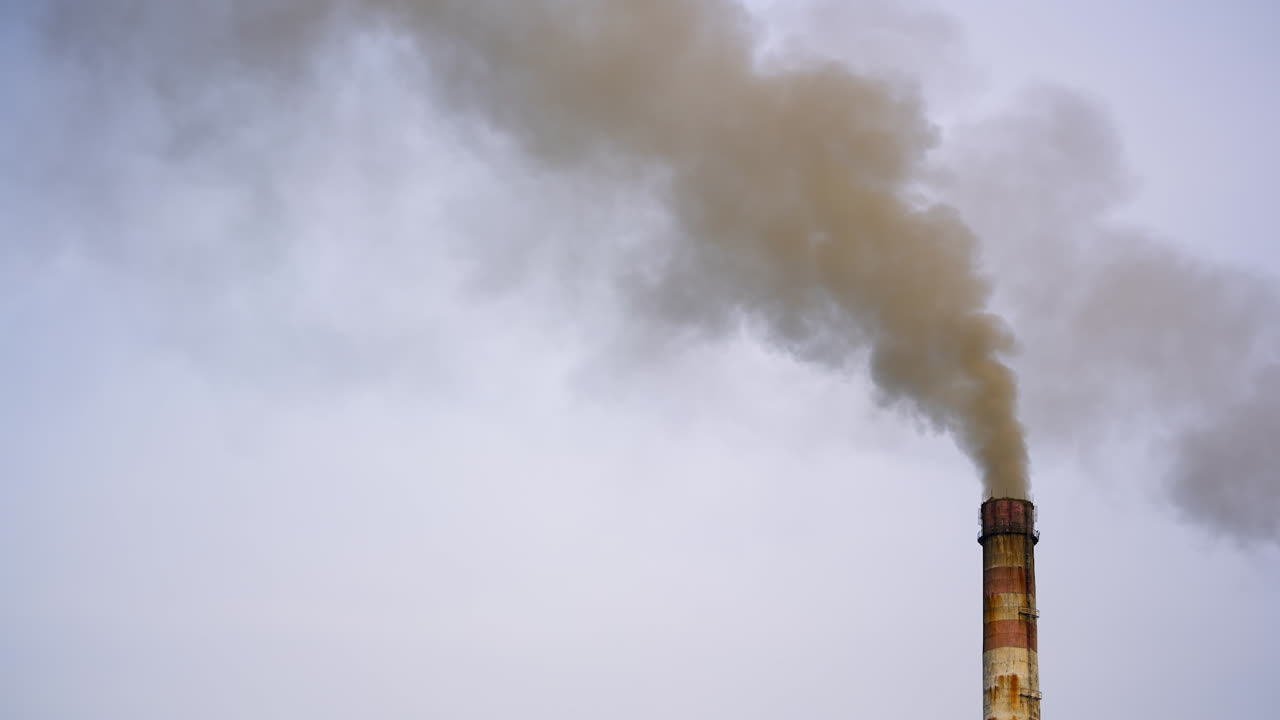 Pollution by industrial production. Fuming pipe power plant against the cloudy sky