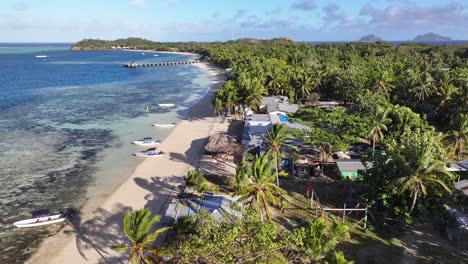 wooden boats on the white sand shore of mana island, mamanuca islands, fiji. aerial drone shot
