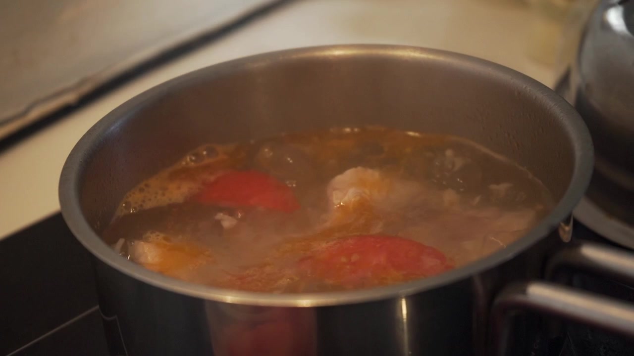 Acqua che bolle mentre si cucina la zuppa di pomodoro. L'inquadratura della telecamera orbita al rallentatore