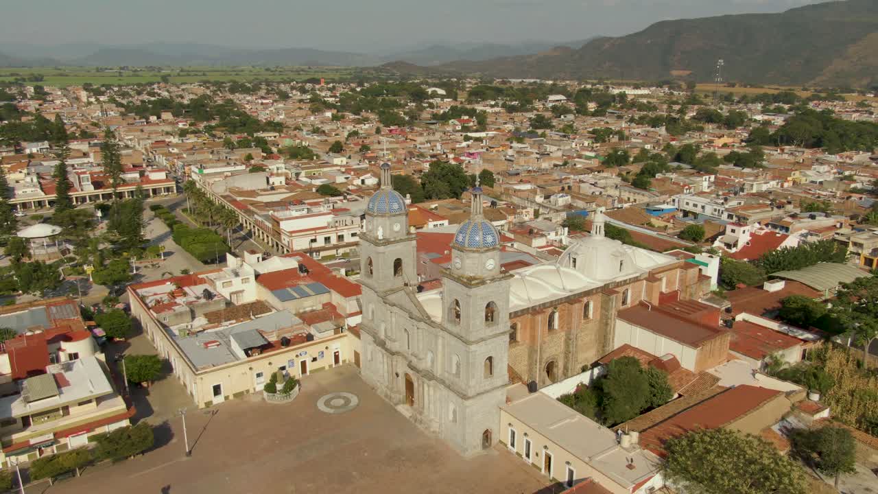 San Juan Bautista Temple with twin bell towers and domes, surrounded by colonial buildings and mountains, Tuxpan, Mexico. Aerial orbit