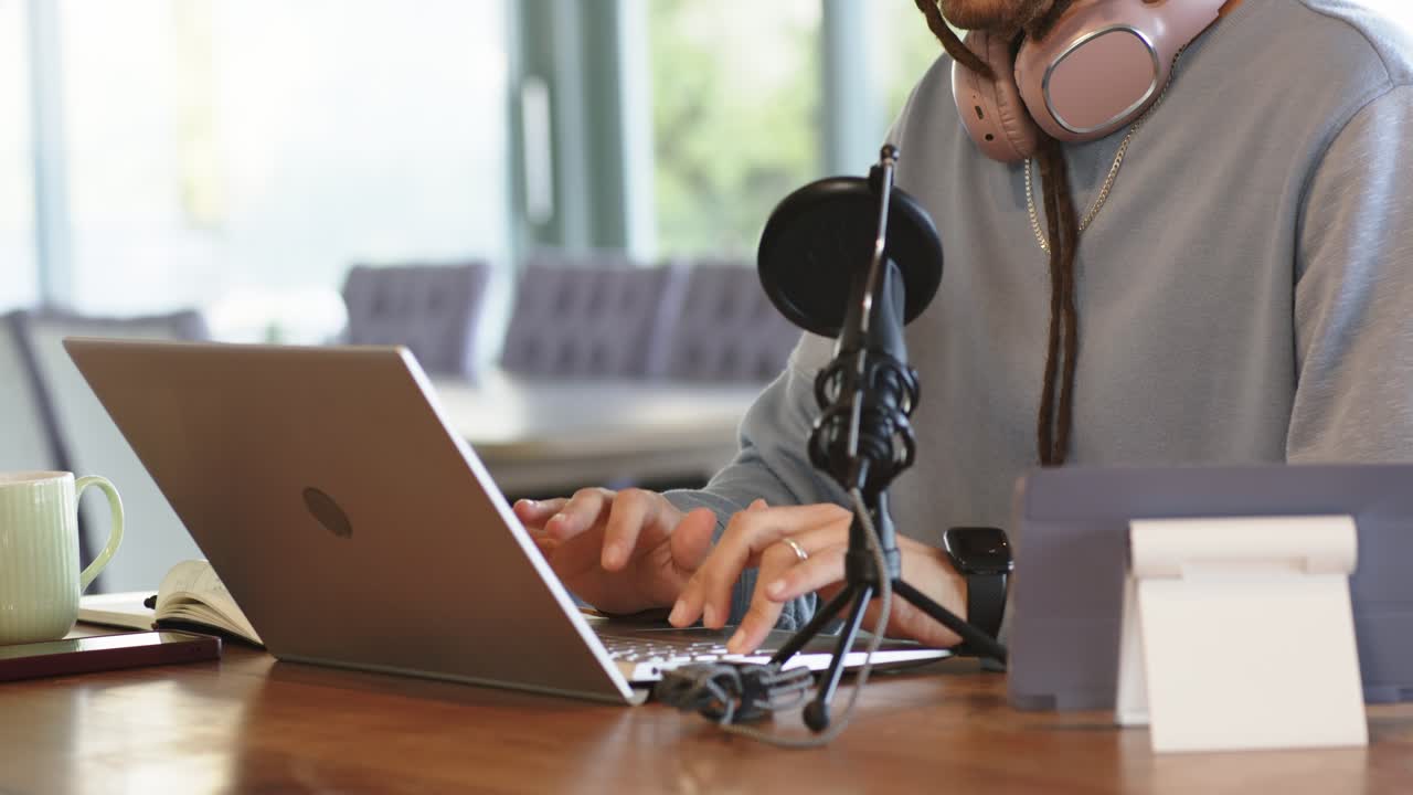 Il content creator si sistema il berretto di lana e si sposta in avanti iniziando a digitare gli appunti del podcast sul portatile