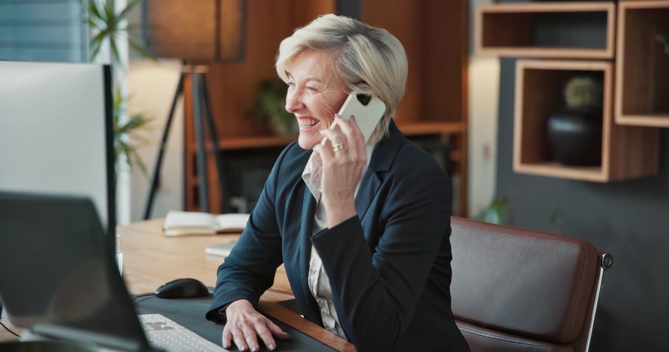 Mature Businesswoman Laughing While Talking on Smartphone in Office