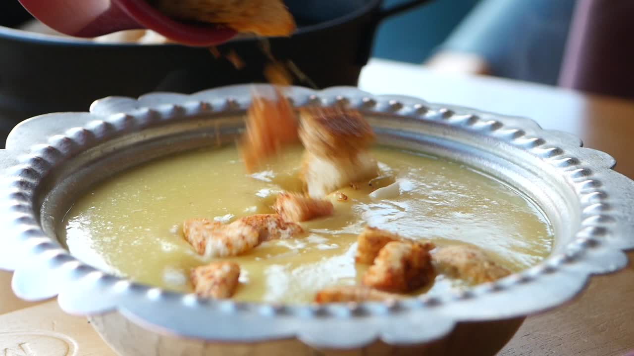 cerca de un plato de sopa cremosa con croutones