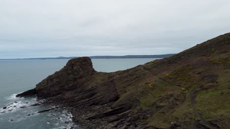 hiker walking along coast path with rickets head and dramatic coastline and crashing waves pembrokeshire uk 4k