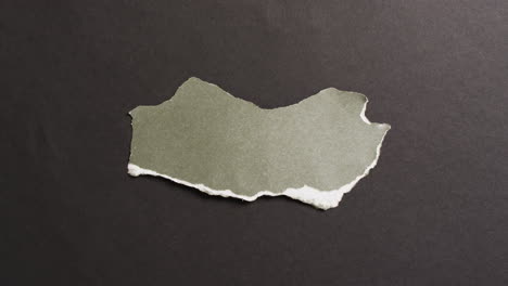 video de primer plano de un pedazo de papel verde roto sobre un fondo negro