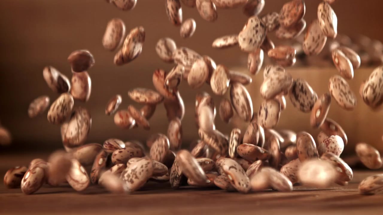 Raw Pinto Beans Falling and Scattering on a Wooden Surface