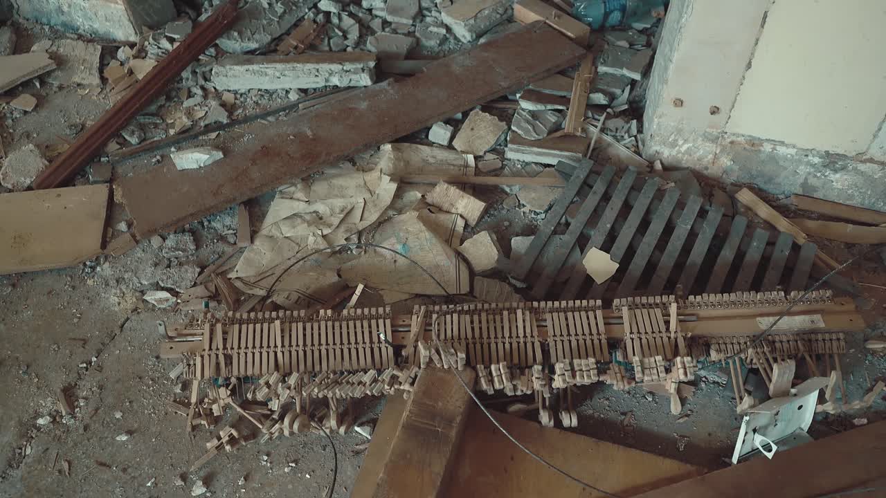 Pezzi rotti di un pianoforte giacciono in un edificio in rovina tra i rifiuti.