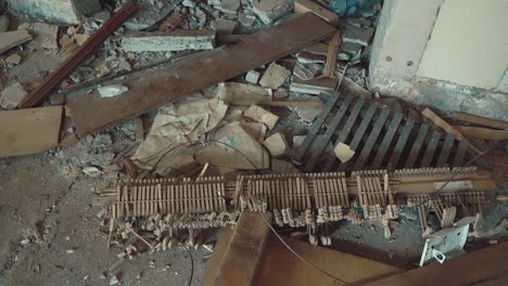 broken parts of a piano lie in a ruined building amidst garbage