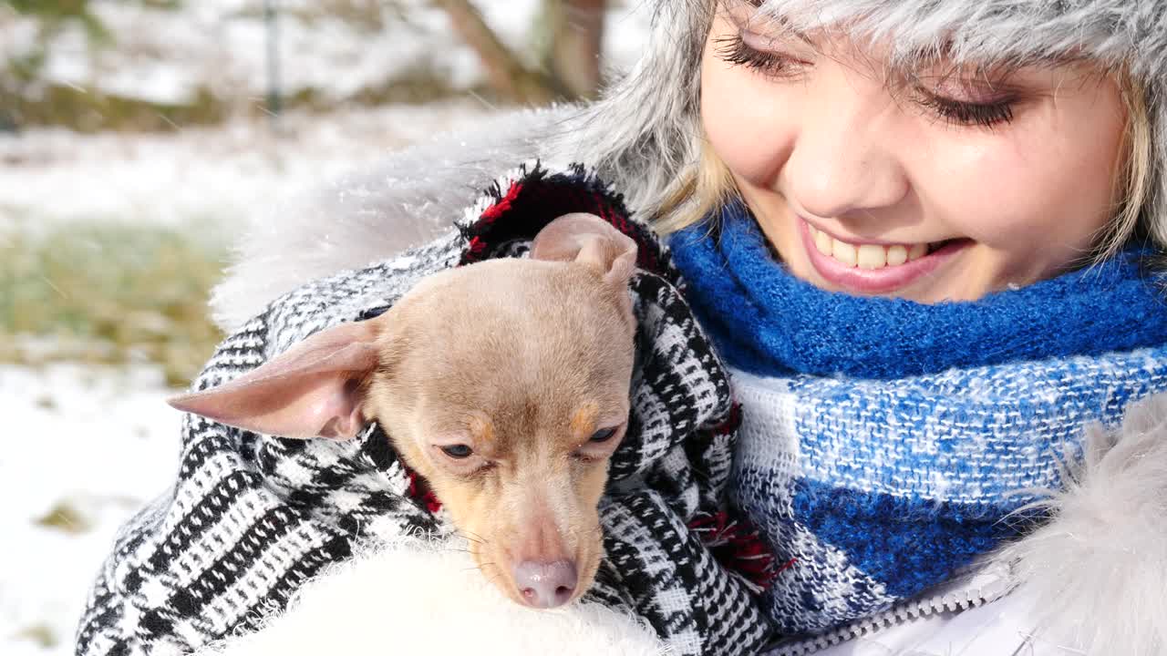 여자 는 겨울 밖 에서 작은 개 와 함께 놀고 있다